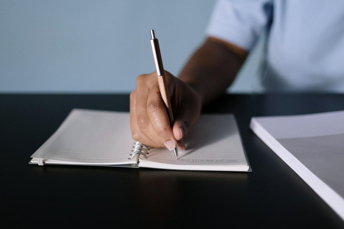 Hand schreibt Notizen in ein Heft