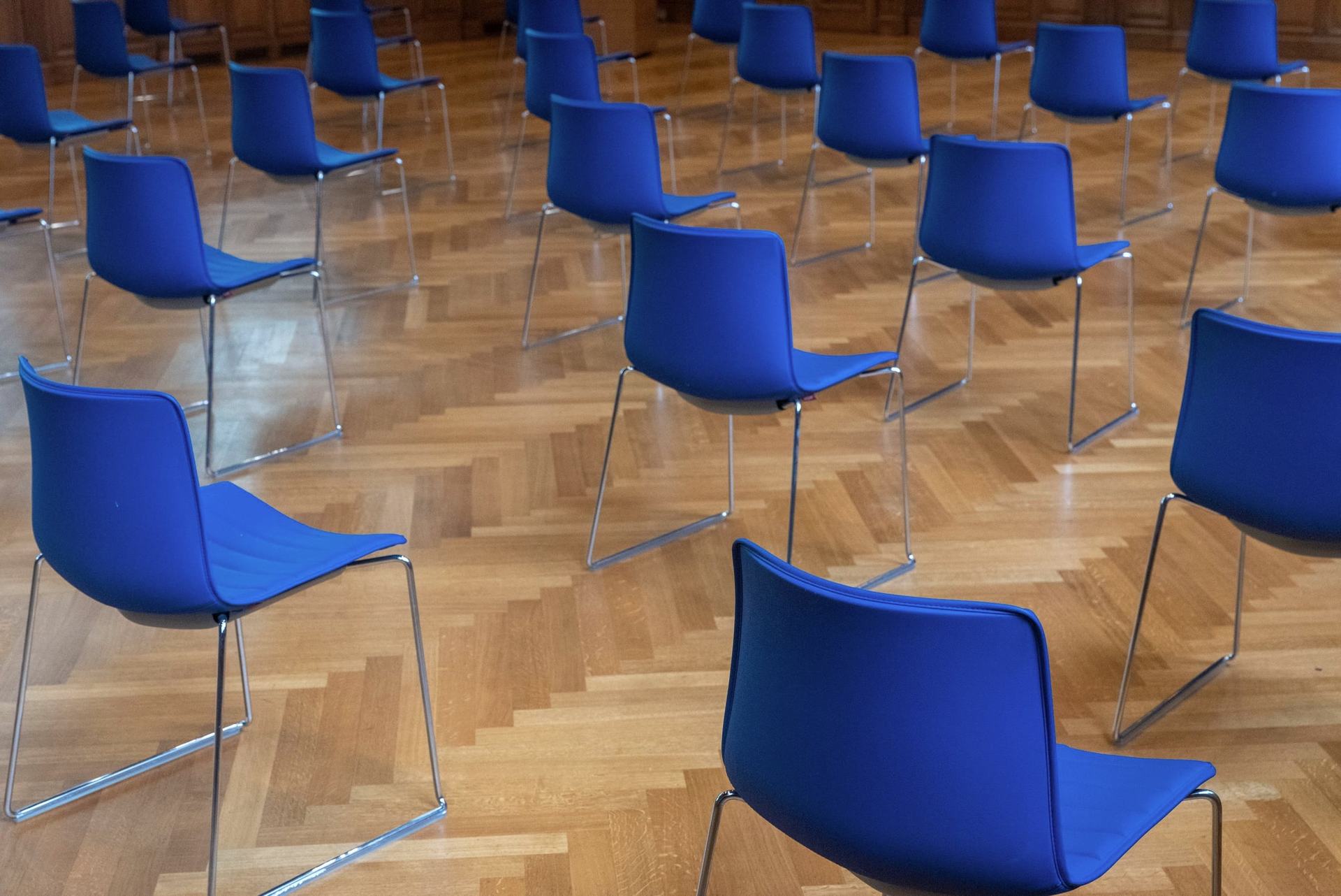 Leerer Schulungsraum mit blauen Stühlen auf Parkett, bereit für die nächste Schulung