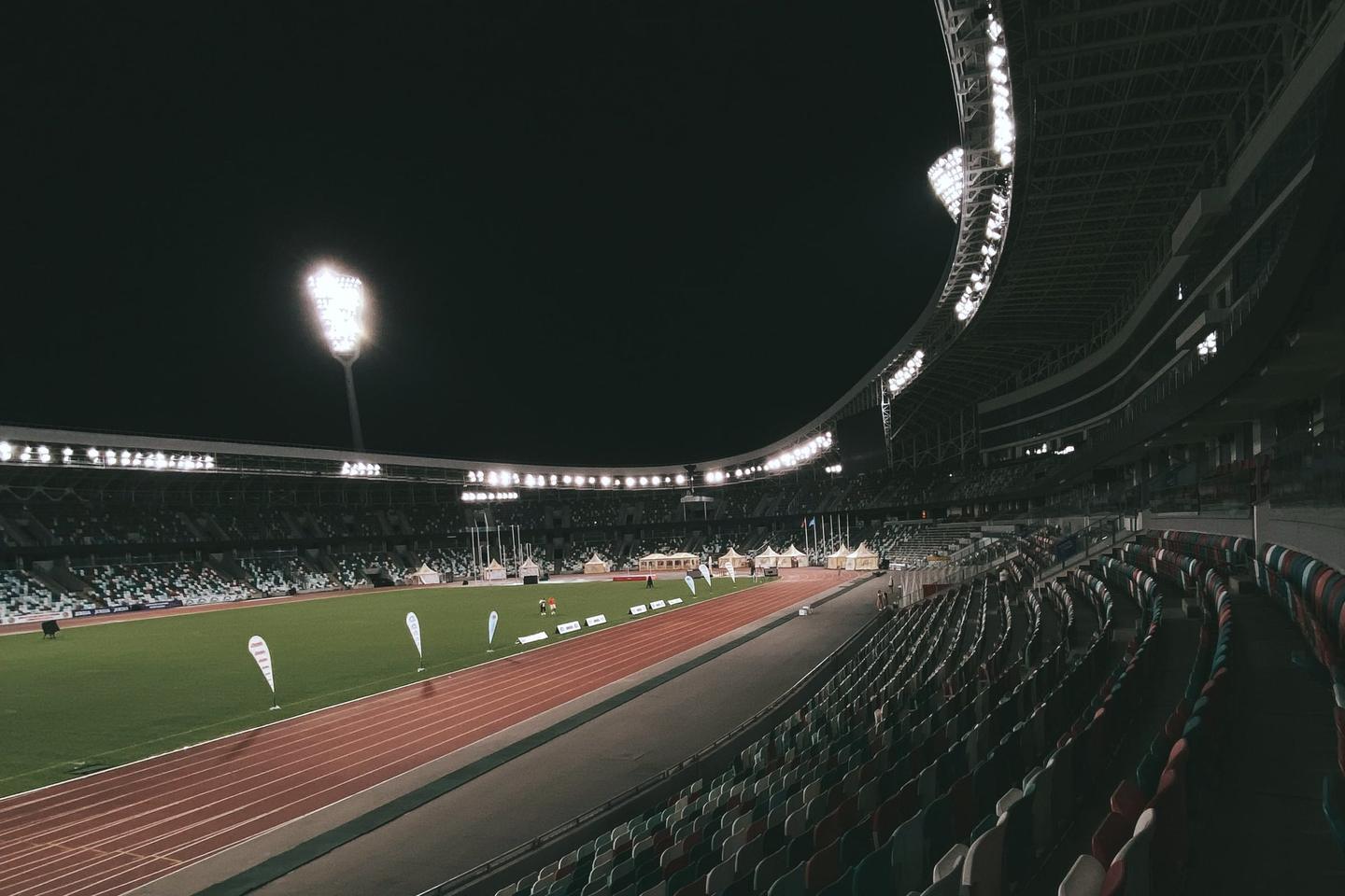 Beleuchtetes Stadion bei Nacht mit leeren Rängen